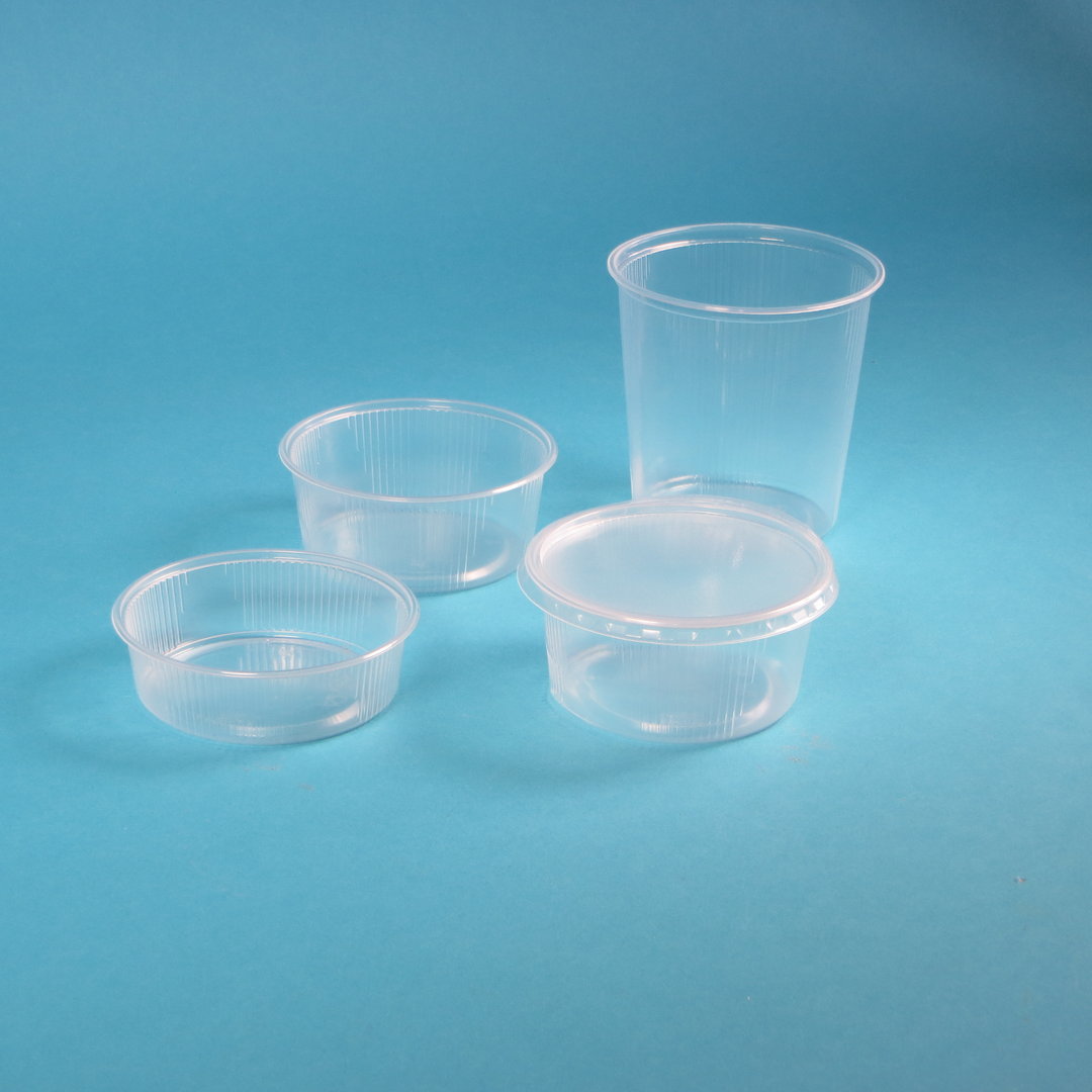 Vier durchsichtige Kunststoffbecher und -behälter mit Deckel auf blauem Hintergrund.