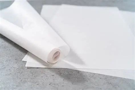 Ein aufgerolltes Blatt weißes Backpapier liegt auf einem anderen Blatt.